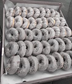 a box filled with lots of doughnuts covered in sprinkled frosting