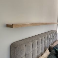 a couch with pillows and a wooden shelf above it