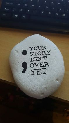 a rock that says your story isn't over yet next to a computer keyboard