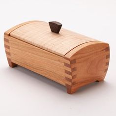 a small wooden box with a black object on it's top sitting on a white surface