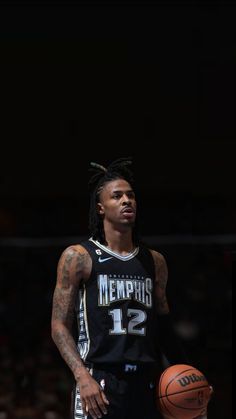 a basketball player with dreadlocks standing in front of a ball and looking at the camera