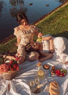 two women are sitting on the grass eating food