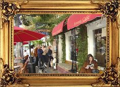 an old gold frame with people walking in front of a coffee shop and red umbrellas