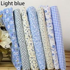 a bunch of blue and white fabric sitting on top of a wooden table next to flowers