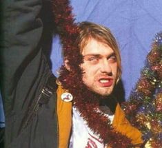 a man wearing a fake christmas garland around his neck and hand in front of him