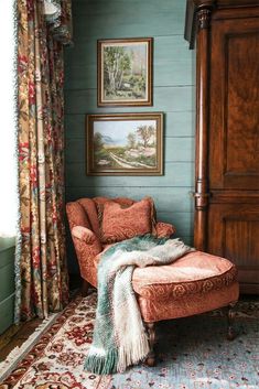 a chair and ottoman in a room with pictures on the wall above it, along with curtains