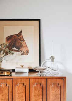 a wooden cabinet sitting next to a wall with a horse painting on top of it