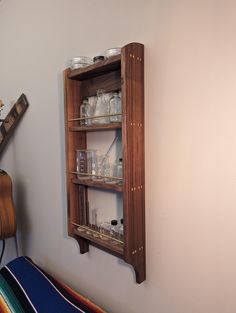 a wooden shelf with jars and glasses on it next to a wall mounted guitar case