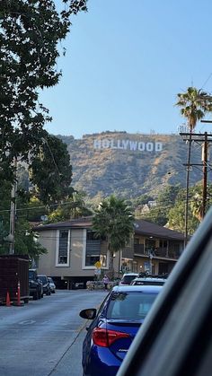 cars are parked on the street in front of hollywood sign