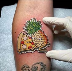 a person with a tattoo on their arm holding a piece of pizza and pineapple