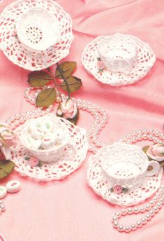 a table topped with pink and white doily covered in lace next to a rose