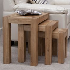 three wooden tables sitting next to each other in front of a white couch with pillows on it