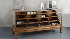 a wooden cabinet with many compartments and shelves on it's sides, in front of a concrete wall