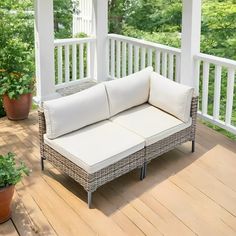 a white couch sitting on top of a wooden deck next to potted plants and trees