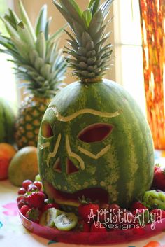 a watermelon mask with fruit around it on a table next to a window