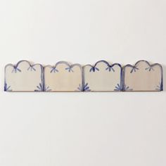 four pieces of blue and white tile with designs on the edges, arranged in a row