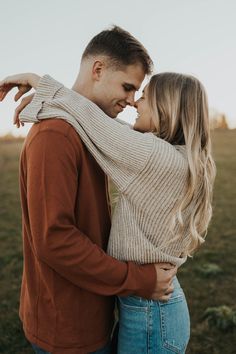 a young man and woman embracing each other in an open field