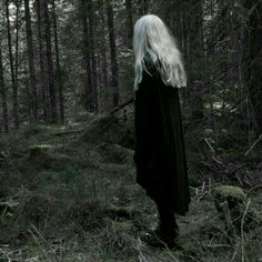 a woman standing in the middle of a forest with long white hair on her head