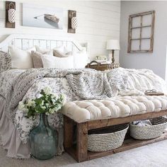 a bed with white sheets and pillows in a room next to a vase filled with flowers