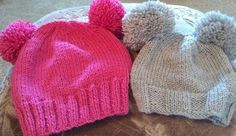 three knitted hats with pom - poms sitting on top of a table