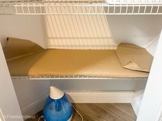 an ironing board on the bottom shelf of a closet