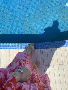 a person laying on the ground next to a swimming pool with their feet in the water