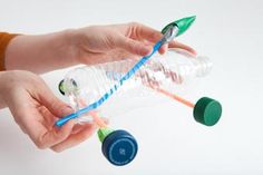 two hands holding plastic bottles with toothbrushes in them and one hand pulling the top