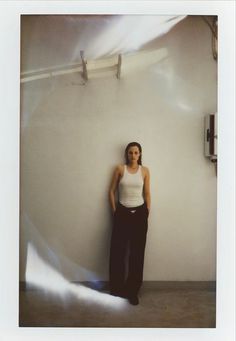 a woman standing in front of a white wall