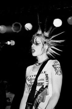 black and white photograph of a woman with her hair in the air, playing guitar