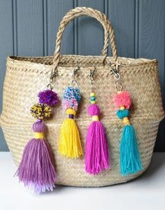 a woven bag with tassels and pom poms hanging from the handles