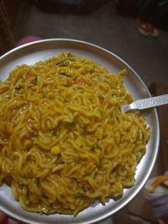 a person holding a plate of noodles on a table