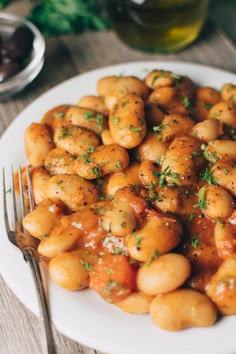 a white plate topped with meat covered in sauce and garnished with parsley