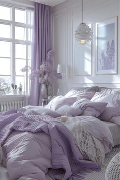 a bed with purple sheets and pillows in a white room next to a large window