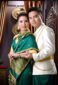 a man and woman dressed in traditional thai garb standing next to each other with their arms around each other