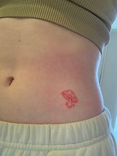 a woman's stomach with a small red tattoo on the side of her belly