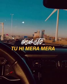 the interior of a car with wind turbines in the back ground and text reading'tu hi mera mera '