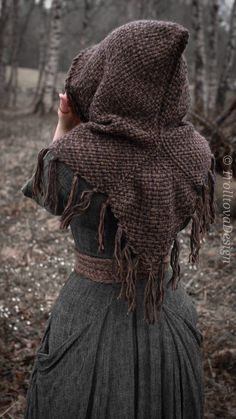 a woman wearing a brown scarf and dress in the woods with her head covered by a shawl