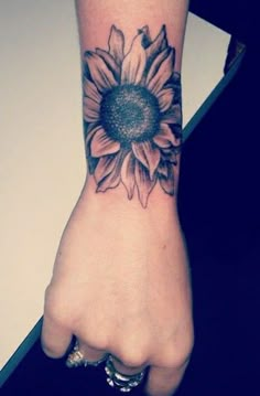 a woman's hand with a sunflower tattoo on the left side of her arm