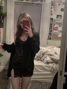 a woman taking a selfie with her cell phone in front of the mirror while wearing fishnet tights and stockings