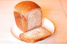 a loaf of bread sitting on top of a white plate next to a slice of bread