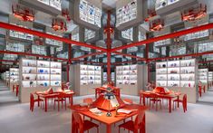 the interior of a store with red tables and chairs in front of bookshelves