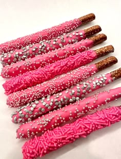 five pink and silver decorated sticks on a white surface