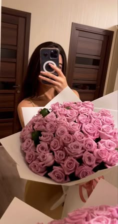 a woman taking a selfie while holding a bouquet of pink roses