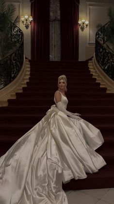 a woman in a white dress standing on some stairs