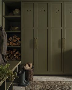 a room with green cupboards and lots of wood in the corner, along with a rug on the floor