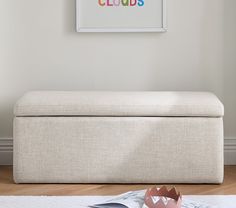 a white bench sitting on top of a hard wood floor next to a framed poster