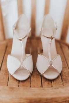 a pair of white high heels sitting on top of a wooden floor