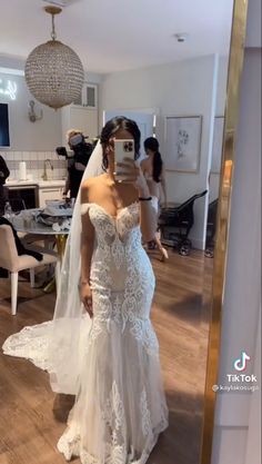 a woman in a wedding dress taking a selfie with her cell phone while she is getting ready to walk down the aisle