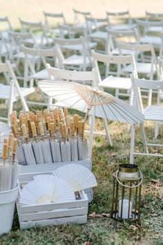 an arrangement of white chairs and umbrellas on the grass near a candle holder with candles in it