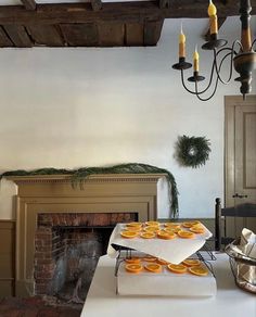 a table with orange slices on it in front of a fire place and chandelier